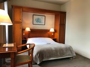 - une chambre avec un lit, un bureau et une chaise dans l'établissement Logis Hôtel-Restaurant Les Airelles, à Neufchâtel-en-Bray