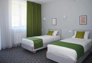 duas camas num quarto com verde e branco em Astra Hotel em Călimăneşti