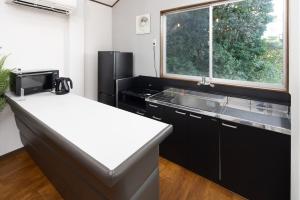 La cuisine est équipée d'un réfrigérateur noir et d'un évier. dans l'établissement ラフネ　白沙の宿, à Shirahama