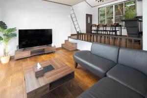 sala de estar con sofá y TV de pantalla plana en ラフネ　白沙の宿, en Shirahama
