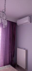 - une chambre avec un rideau violet et un lustre dans l'établissement Maria's home, à Órmos