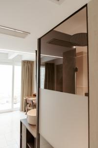 La salle de bains est pourvue d'un grand miroir et d'un lavabo. dans l'établissement Le Carasse Boutique Hotel, à Mola di Bari