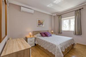 Un dormitorio con una cama con almohadas moradas y una ventana en Rinaldis, en Kaštelir