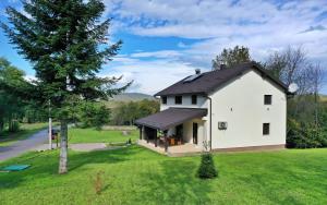 a white house with a black roof on a green field at Villa Diva Grabovčeva in Rakovica