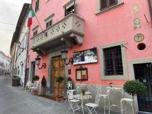 un edificio rosa con mesas y sillas en una calle en Quattro Gigli Palace, en Montopoli in Val dʼArno