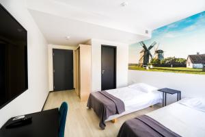 1 dormitorio con 2 camas y una pintura de un molino de viento en Hotel NOSPA, en Kuressaare