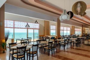 um restaurante com mesas e cadeiras e vista para o oceano em Midia Family Resort All-Inclusive em Aheloy