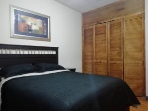 um quarto com uma cama preta e armários de madeira em Departamento Equipado á 3 minutos del Consulado americano 2 RECAMARAS em Manuel F. Martínez