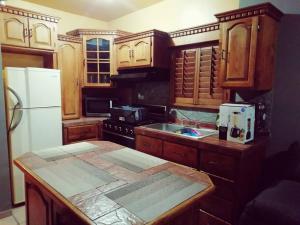 uma cozinha com armários de madeira e um frigorífico branco em Departamento Equipado á 3 minutos del Consulado americano 2 RECAMARAS em Manuel F. Martínez