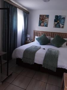 a bedroom with a large white bed with green pillows at Sleep@161 Benade Drive in Bloemfontein