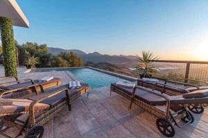 a swimming pool with chairs and a view of the mountains at Villa Fahrenheit in El Gastor