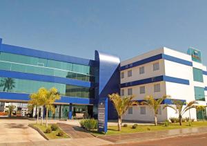 a blue and white building with palm trees in front of it at Bernal Hotel Econômico in Ituiutaba