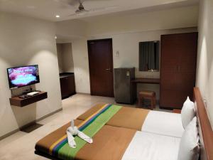 a hotel room with a bed and a television at Hotel Sumanchandra Suites in Nashik