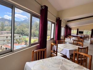 un ristorante con tavoli, sedie e ampie finestre di Lavender Garden Hotel a Tsavo