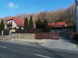 a house with a fence and a stone wall at Bóbita Háza in Eplény