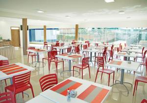a room filled with tables and red chairs at Bernal Hotel Econômico in Ituiutaba