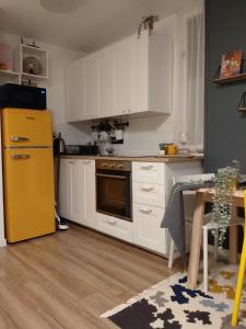 Apartman 7th Heaven في زغرب: مطبخ فيه دواليب بيضاء وثلاجة صفراء