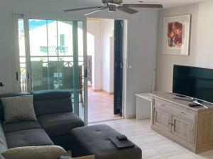 a living room with a couch and a flat screen tv at Rocas del Mar with heated Pool and double Terrace in Costa Del Silencio