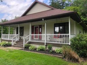 ein kleines grünes Haus mit einer weißen Veranda und einer Treppe in der Unterkunft 3640 Wells Bay Road home in Ashville