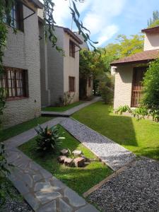 a garden with a walkway in front of a house at Cabañas El Refugio in Chascomús