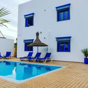 Villa mit einem Pool und blauen Stühlen in der Unterkunft Dar Iziki in Sidi Kaouki