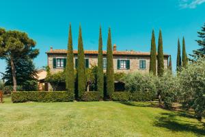 a house with cypress trees in front of a yard at Agriturismo Il Borgo in Cortona
