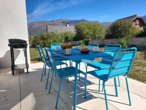 una mesa azul y sillas en un patio con parrilla en Gîte les gentianes Fleurs des Pyrénées en Argelès-Gazost
