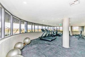 a gym with cardio equipment in a building with windows at Entire apartment with lake view in Tuggeranong