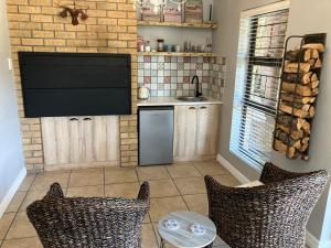 a kitchen with a television and two chairs at UpperRoom Ceres -Indoor Braai in Ceres