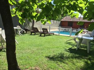 een tuin met banken en een zwembad en een boom bij Yatale II in Chascomús