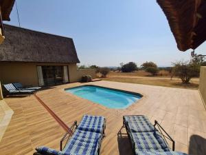 deux chaises longues et une piscine dans une cour dans l'établissement Moshate Lodge Zebula 4 Bedroom Holiday home, à Mabula