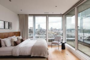 um quarto com uma cama grande e uma janela grande em The Canary Wharf Secret - Glamorous 3BDR Flat with Terrace and Parking em Londres