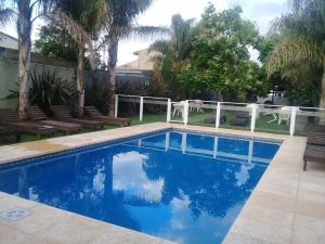 a swimming pool in a backyard with a white fence at Yatale II in Chascomús
