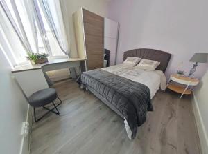 a bedroom with a bed and a chair and windows at Logement Place d'Erlon hypercentre avec balcon in Reims