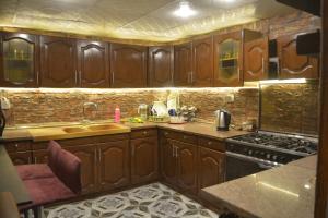 a kitchen with wooden cabinets and a stove at Waterfall Hut - Live by a waterfall كوخ الشلال - عش وسط شلال in Amman