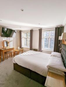 a bedroom with a large bed and a flat screen tv at Hotel Celebrity in Bournemouth