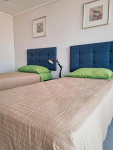 1 dormitorio con 2 camas, cabeceros azules y lámpara en Exclusivo Departamento a Pasos de la Playa en Viña en Viña del Mar