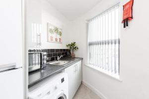 eine weiße Küche mit einem Waschbecken und einem Fenster in der Unterkunft St Marys Studios-Free Street Parking in Liverpool