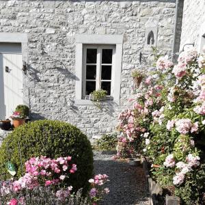 una casa de piedra con flores rosas y una ventana en A l'ombre du noyer, en Fernelmont