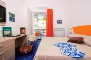 Schlafzimmer mit einem Bett, einem Schreibtisch und einem Fenster in der Unterkunft Maison Escher in Atrani