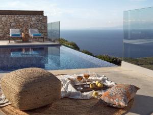 einen Tisch mit Weingläsern und ein Tablett mit Essen neben einem Pool in der Unterkunft Akron Luxury Suites in Koríthion