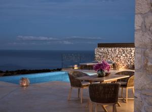 a patio with a table and chairs and a pool at Akron Luxury Suites in Koríthion