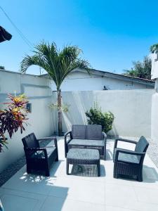 un patio con sillas, mesas y una palmera en Résidence Palms Abidjan en Abiyán