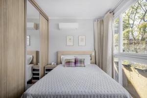 a bedroom with a bed and a large window at Gramado Garden Centro in Gramado