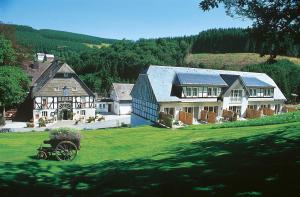 uma casa grande no topo de um campo verde em Hotel Gut Vorwald em Schmallenberg