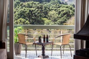 a patio with two chairs and a table with bottles on it at Incrível Vista no Capivari com 4 Quartos e Lareira in Campos do Jordão