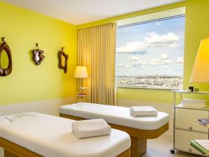 a room with two beds and a large window at Too Hotel Paris - MGallery in Paris