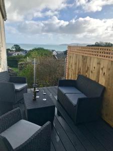 un patio con 2 divani, tavolo e sedie di Traeth Arian Cottage a Benllech