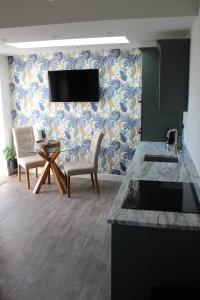 a kitchen with two chairs and a tv on a wall at Traeth Arian Cottage in Benllech