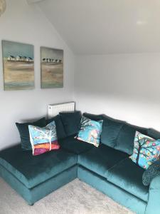 um sofá verde numa sala de estar com almofadas em Traeth Arian Cottage em Benllech